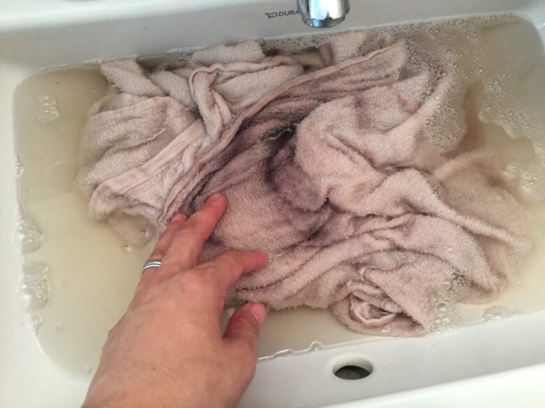 白髪染めシャンプー(グローリンワンクロス)でシャンプーした後のタオルを予洗いしている様子。